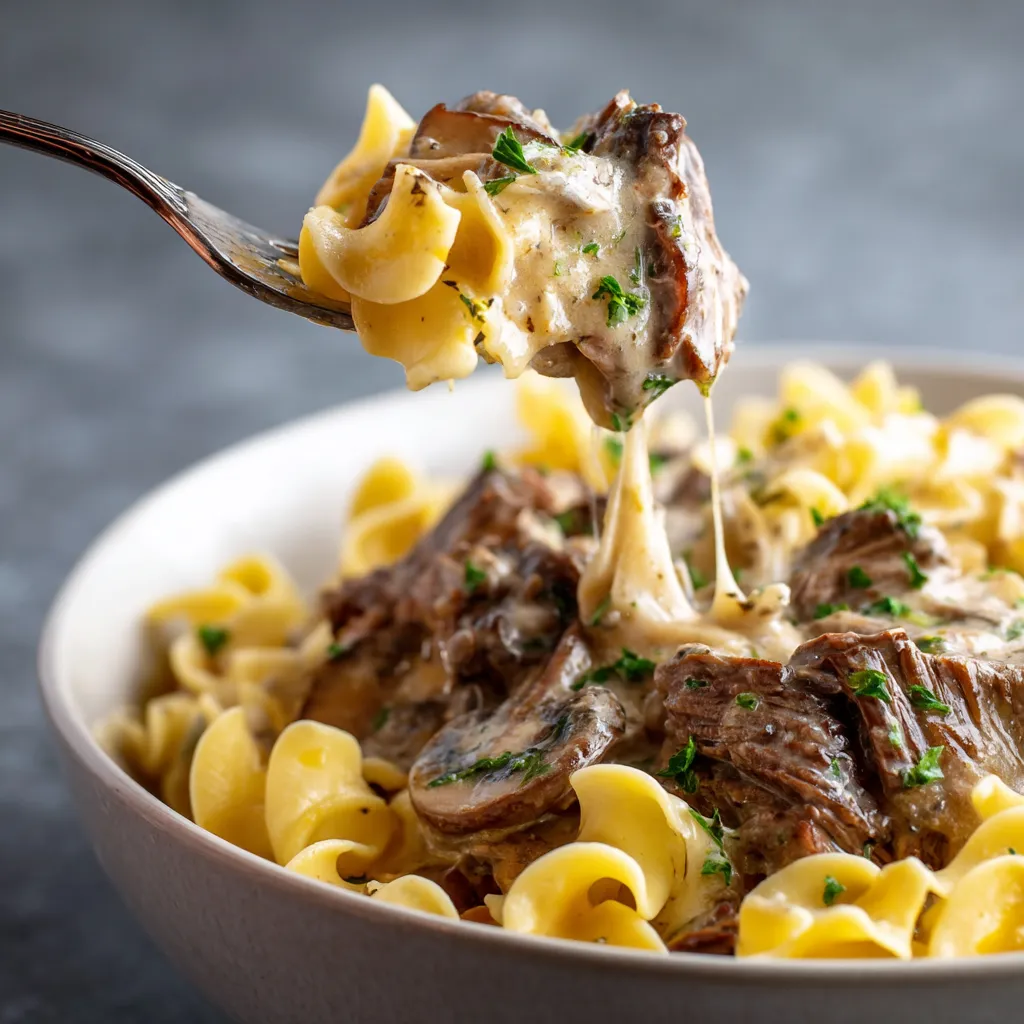 A bowl of beef stroganoff with a fork in it.