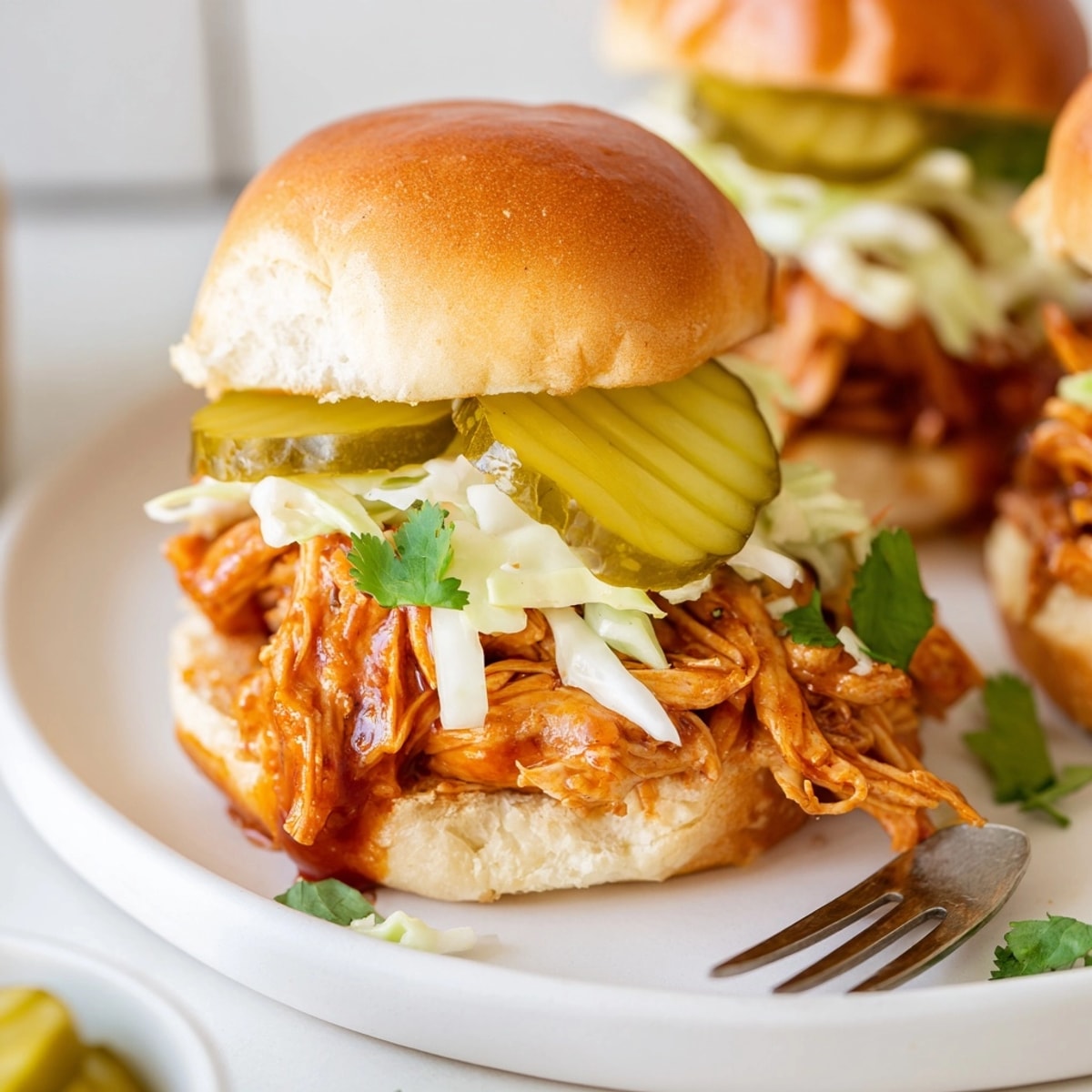 Stacked Cajun BBQ Chicken Sliders overflowing with slaw—tangy, messy, and totally delicious!