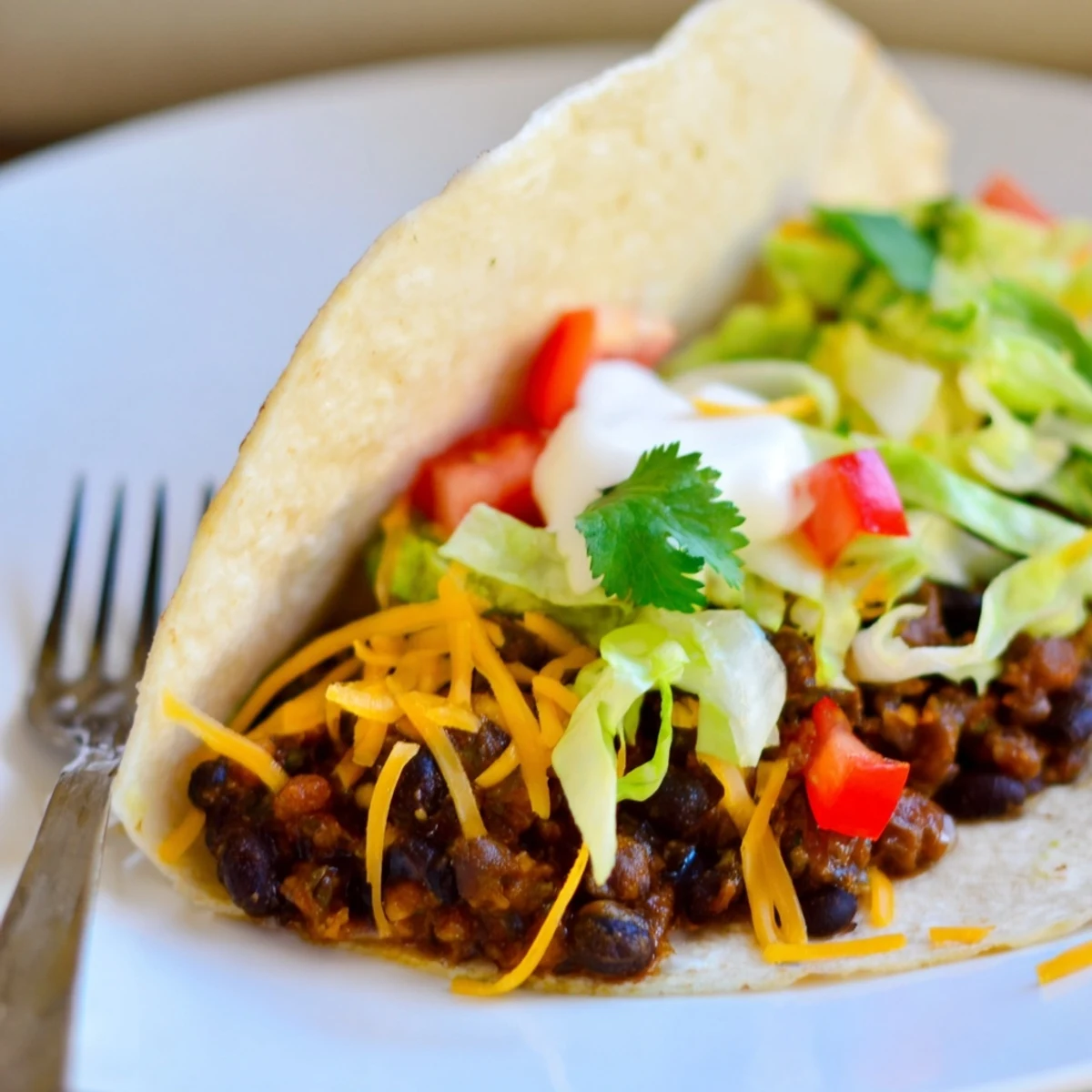 Zesty Cheesy Cajun Black Bean Tacos garnished with fresh veggies and lime wedges.