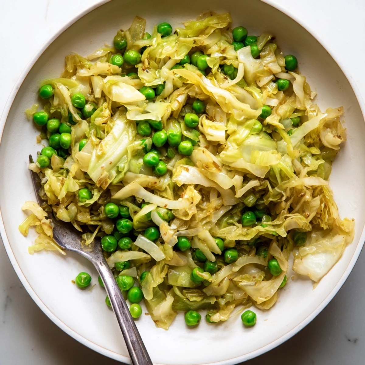 Freshly cooked cabbage stir-fry with soy sauce, garlic, and bright green peas, perfect alongside rice.