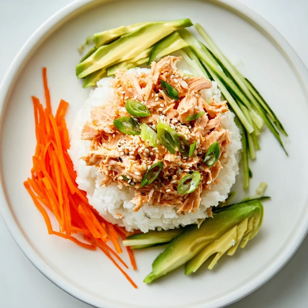 Flaky canned salmon mixed with sriracha mayo atop rice, garnished for a delicious Spicy Canned Salmon Rice Bowl.