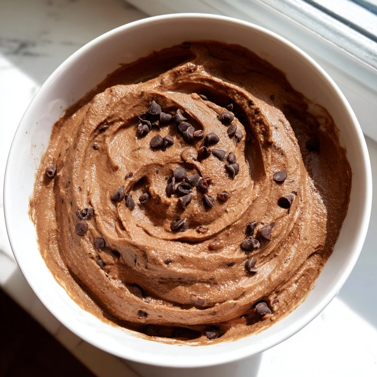 Rich, dark chocolate hummus swirled in a serving bowl, perfect with fresh strawberries for dipping.