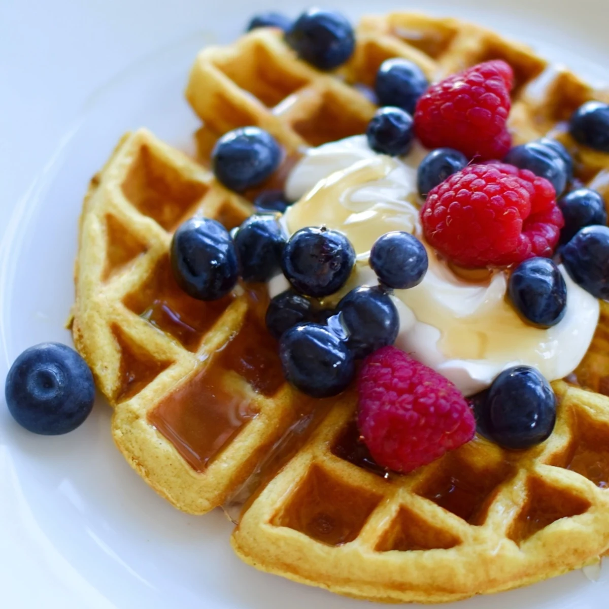 Golden, fluffy Anti-Inflammatory Adaptogenic Turmeric Waffles dusted with warm spices and topped with fresh berries.