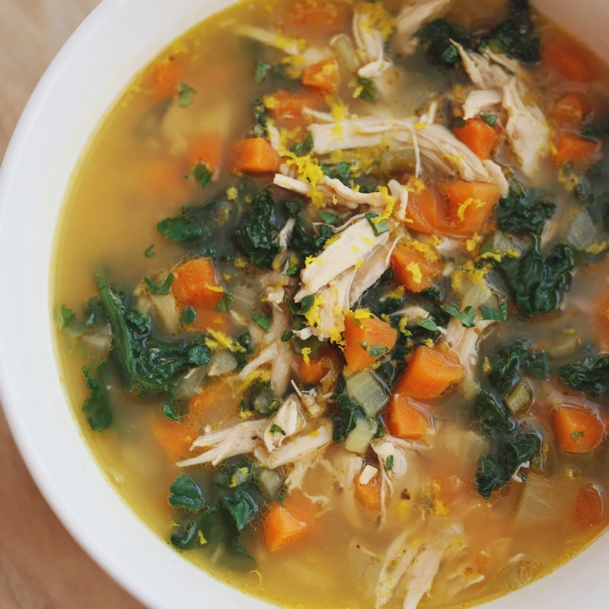Golden High Protein Lemon and Turmeric Chicken Soup steams in a rustic bowl, garnished with lemon wedges and fresh parsley, perfect for a nourishing lunch.