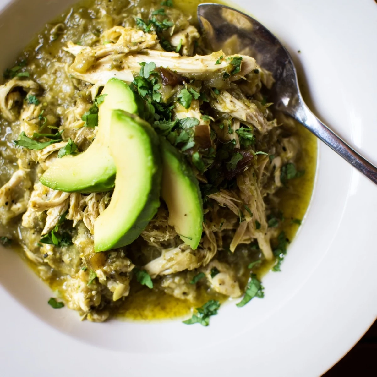 A steaming bowl of Chicken Chili Verde served with lime wedges and warm tortillas, perfect for a cozy dinner.