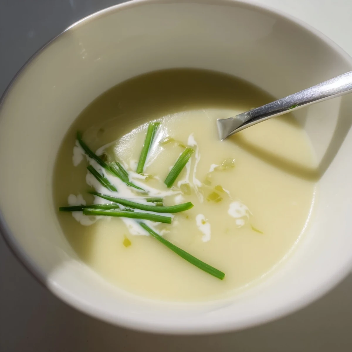 Creamy potato leek soup simmering in a pot, garnished with fresh chives and a swirl of cream for a comforting French-style meal.