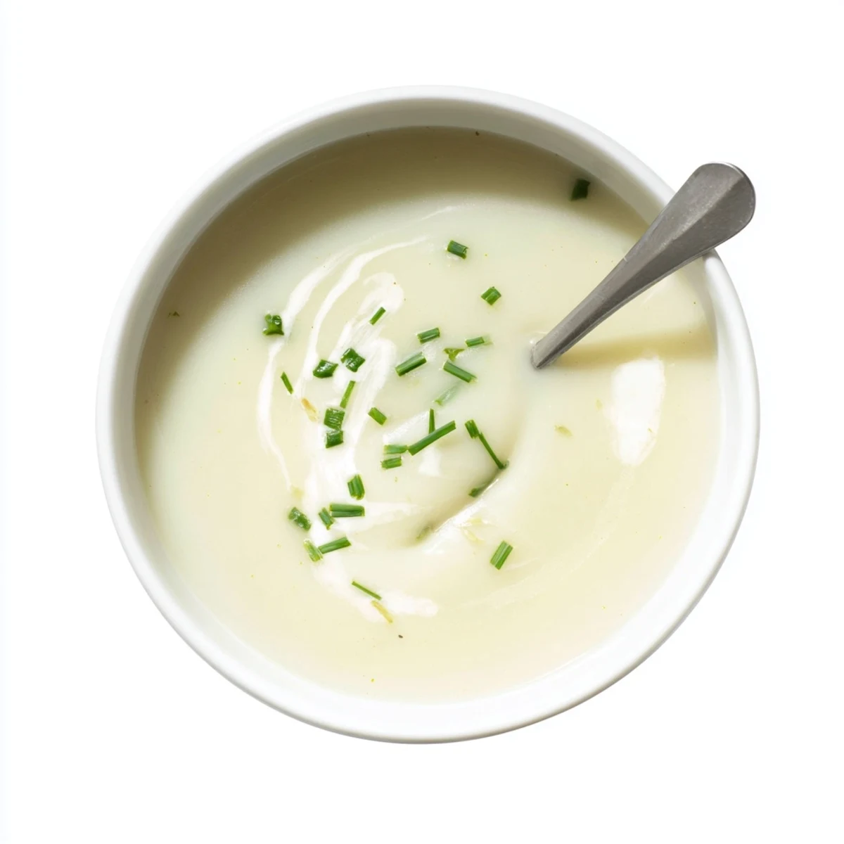 Bowl of velvety potato leek soup topped with chopped chives, served alongside crusty bread for a hearty vegetarian lunch or dinner.