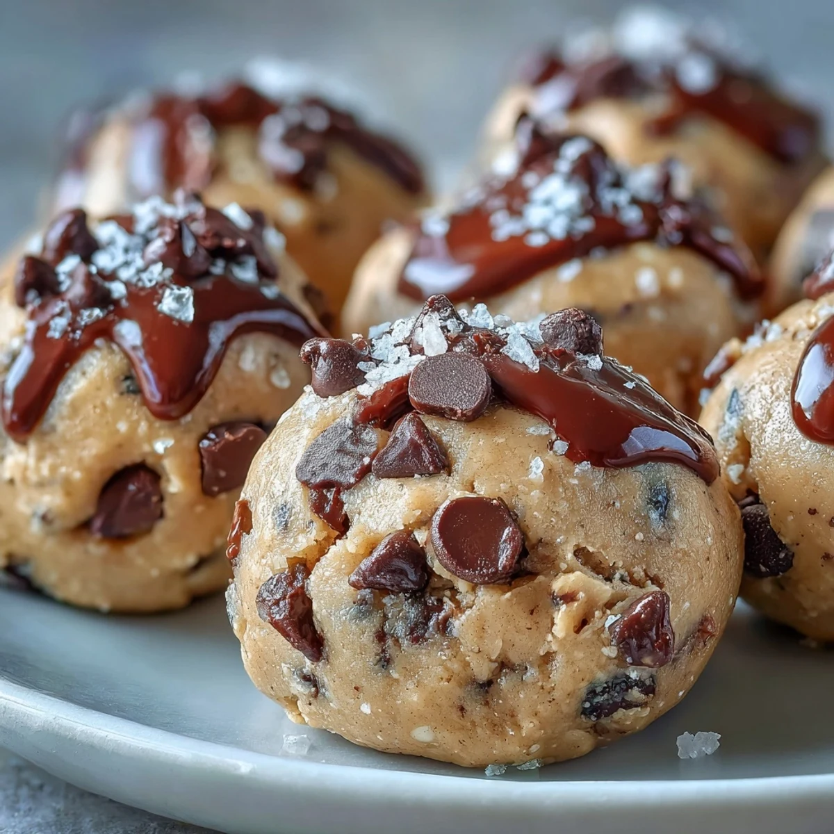 A hand reaches for a Vegan Chickpea Cookie Dough Bite with Dark Chocolate Chips.