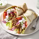 Savor beef shawarma wraps, drizzled with tangy yogurt sauce in warm flatbread.  