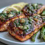 A vibrant plate of Marry Me Salmon with roasted asparagus and lemon wedges, flaking easily with a fork to reveal tender, moist flakes.  
