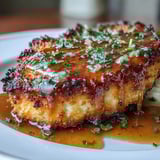 Tender, pan-fried Parmesan crusted chicken breasts topped with silky lemon butter sauce and fresh parsley for a family dinner.