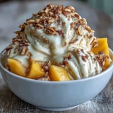Vibrant Vegan Mango Coconut Ice Cream Bowls with crunchy toasted oats, topped with fresh mint and mango pieces.