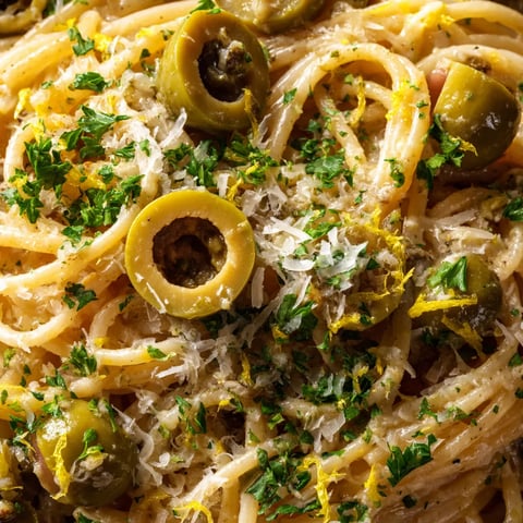 A plate of pasta with olives and cheese.