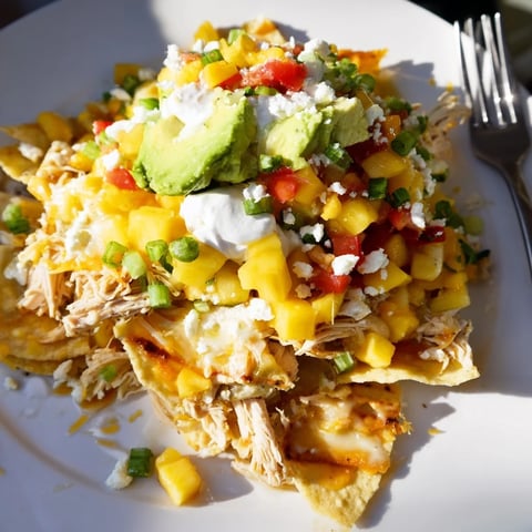 Crispy Mango Pineapple Chicken Nachos topped with vibrant salsa and melted cheese.  