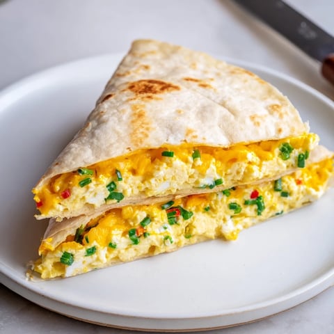 Creamy ricotta cheddar breakfast quesadilla paired with fresh herbs and scrambled eggs.  