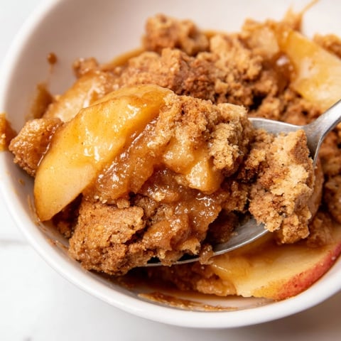 Warm Gingerbread Caramel Apple Cobbler topped with vanilla ice cream, inviting autumn flavors.