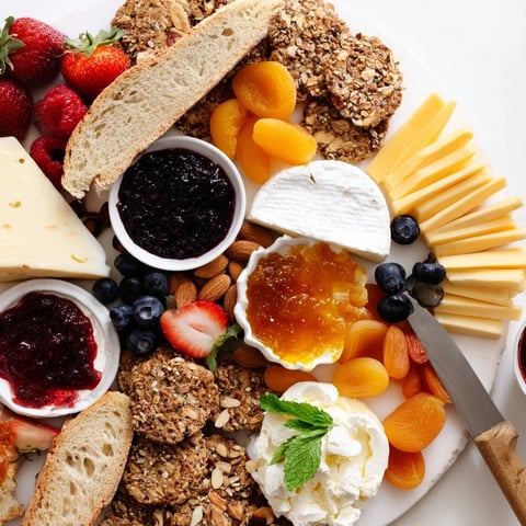 Vibrant jam-infused brunch board with fruits, cheeses, and artisan breads.  