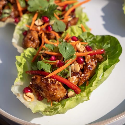Korean BBQ Chicken Lettuce Wraps with glistening, grilled chicken, fresh veggies, and bright pomegranate seeds.