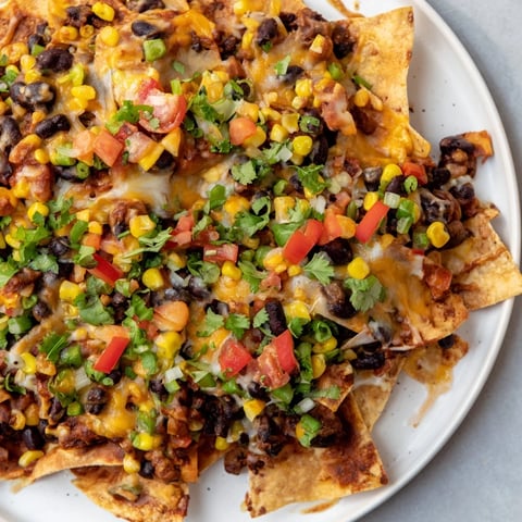 Sheet-pan nachos featuring melted cheddar, colorful veggies, and a delicious combination of flavors.