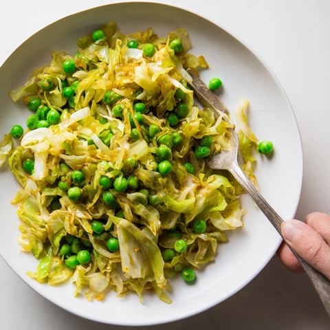 Steaming cabbage stir-fry with garlic, soy & peas, a delicious vegan side dish, ready to eat.