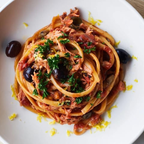 Golden brown pasta with tuna, olives, and capers, ready to be enjoyed with fresh parsley.
