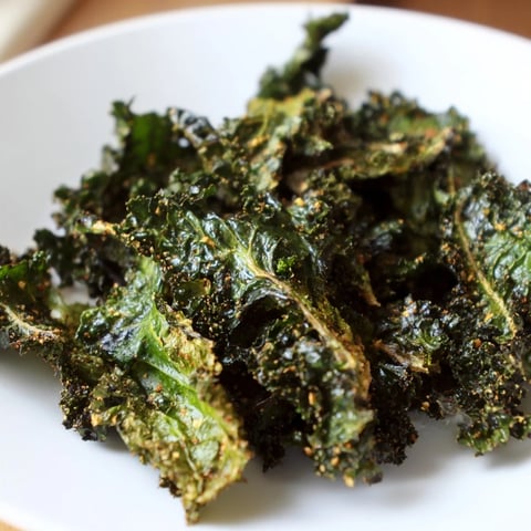 Golden, crispy baked kale chips, a healthy snack with sea salt and pepper seasoning.