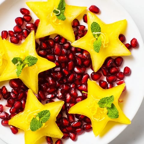 Vibrant pomegranate and mint star fruit platter with glistening pomegranate seeds, ideal for a snack.