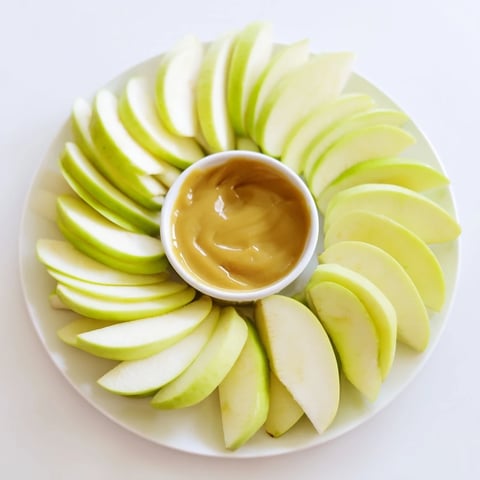 Platter of crisp apple slices encircling a glistening, homemade caramel dip, a perfect Apple Slices treat.