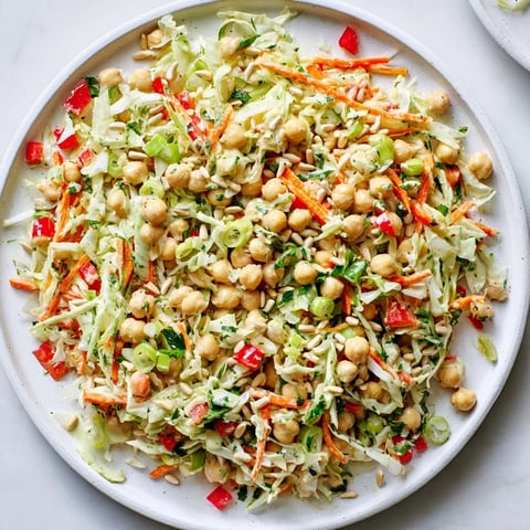 A colorful bowl of Fiber-Forward Chickpea Salad, ready to eat, with creamy tahini dressing.