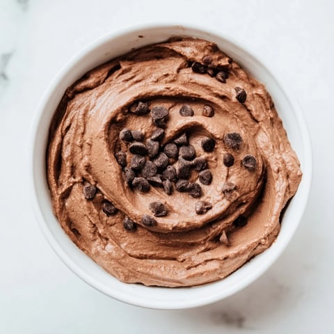 A bowl of smooth chocolate hummus, a sweet vegan dip ready for fruit and snacking.
