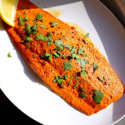 Golden, flaky Indian Tikka Salmon served with fresh cilantro and a bright lemon wedge.