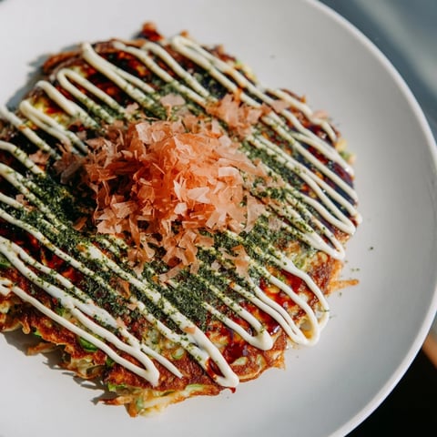 Golden-brown Japanese okonomiyaki pancakes, savory and packed with cabbage, served with toppings.