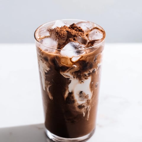 Frothy Milo ice latte, a cool beverage swirled with milk over ice, ideal for summer sipping.