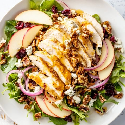 Close-up of a Caramel Apple Chicken Salad, showing fresh apples, chicken, and caramel dressing drizzle.