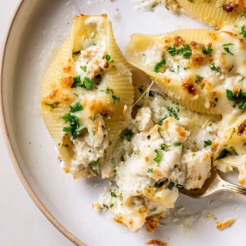 Golden Chicken Alfredo Stuffed Shells bubbling in a baking dish, with a creamy cheese topping.