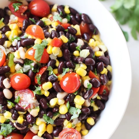 A vibrant Cowboy Caviar salad in a rustic bowl, brimming with black beans, corn, and diced red bell peppers.