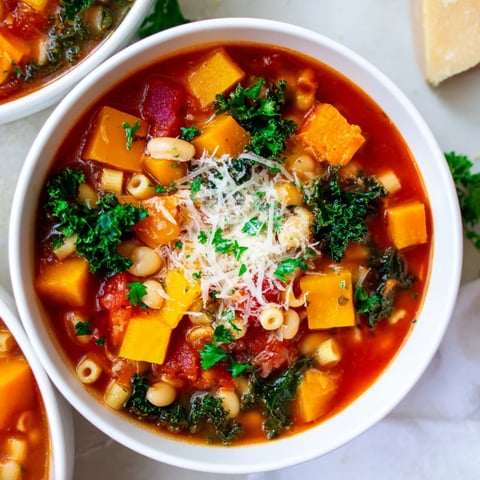 A cozy bowl of Winter Minestrone Soup with Butternut Squash and Kale, topped with Parmesan and fresh parsley.