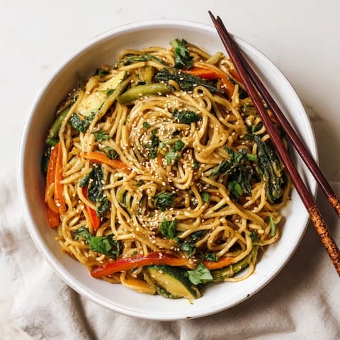 A bowl of noodles with vegetables and sauce.