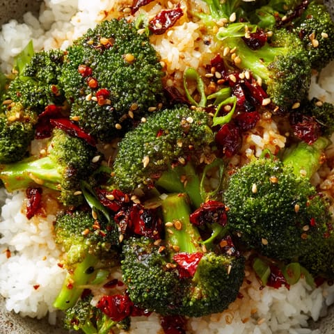 A bowl of rice with broccoli and red peppers.