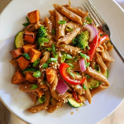 A hearty bowl of Miso Maple Roasted Veggie Pasta topped with fresh herbs and sesame.  