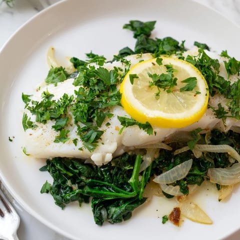 Flaky cod fillets infused with garlic and lemon, beautifully plated with sautéed greens.  