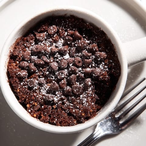 Warm and fluffy microwave mug cake, pictured with a scoop of vanilla ice cream melting down the side.