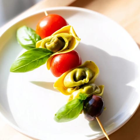 Italian Appetizer Skewers showcasing cheese tortellini tossed in pesto, paired with olives and fresh basil for a vibrant bite.