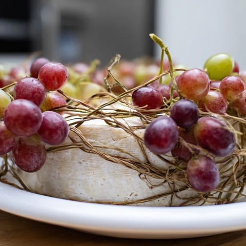 A vibrant The Rustic Vineyard cheese board: artisan cheese and grapes beautifully arranged.