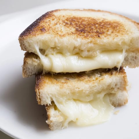 Crispy layers of golden-brown bread surrounding a melty Mozzarella Stick Grilled Cheese, ready to be devoured.