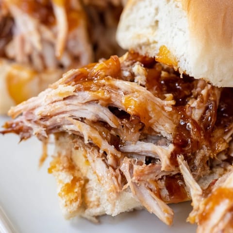 Applesauce pulled pork sandwiches featuring tender shredded meat glistening in a sweet apple glaze.