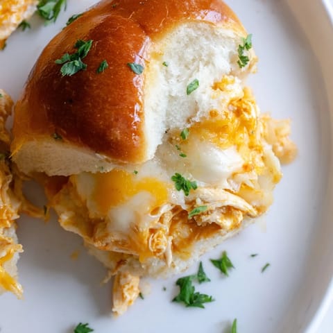 A close-up of cheesy, baked Pizza Dip Sliders with melted mozzarella and cheddar, fresh parsley garnish, ready to serve.