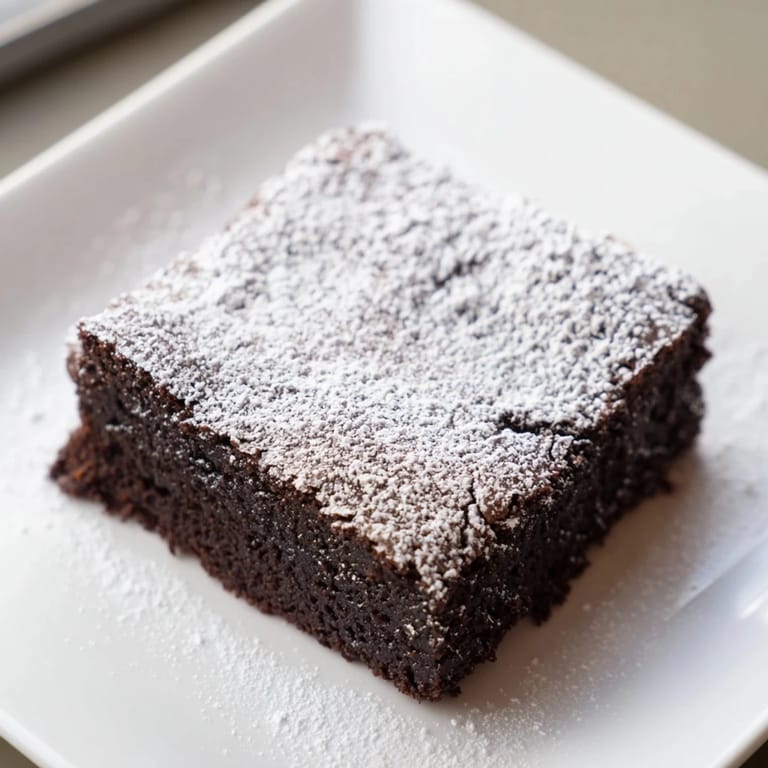 Warm, rich brownie squares, freshly baked and lightly dusted with powdered sugar for a delightful treat.
