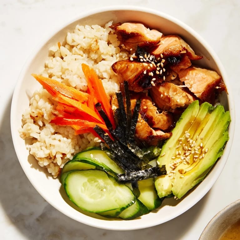Perfectly flaked salmon and sliced chicken atop a delicious Japanese-Style Salmon & Chicken Rice Bowl, ready to be enjoyed.
