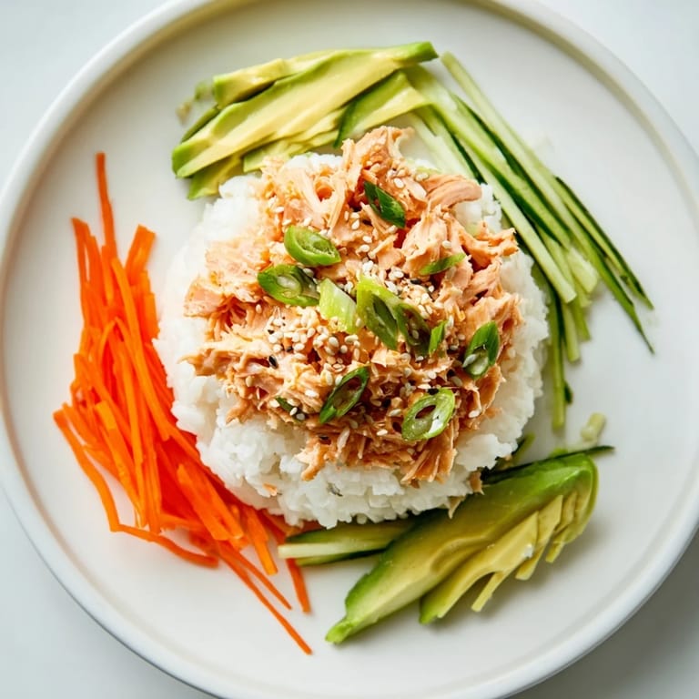 Flaky canned salmon mixed with sriracha mayo atop rice, garnished for a delicious Spicy Canned Salmon Rice Bowl.